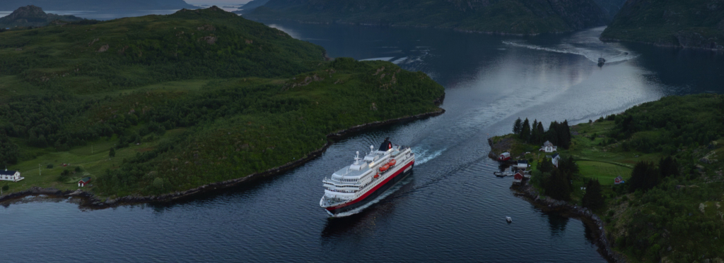Photo of Hurtigruten's MS Richard With surrounded by green landscape. This vessel will make a historic voyage by running on biodiesel making near-zero emissions a possibility